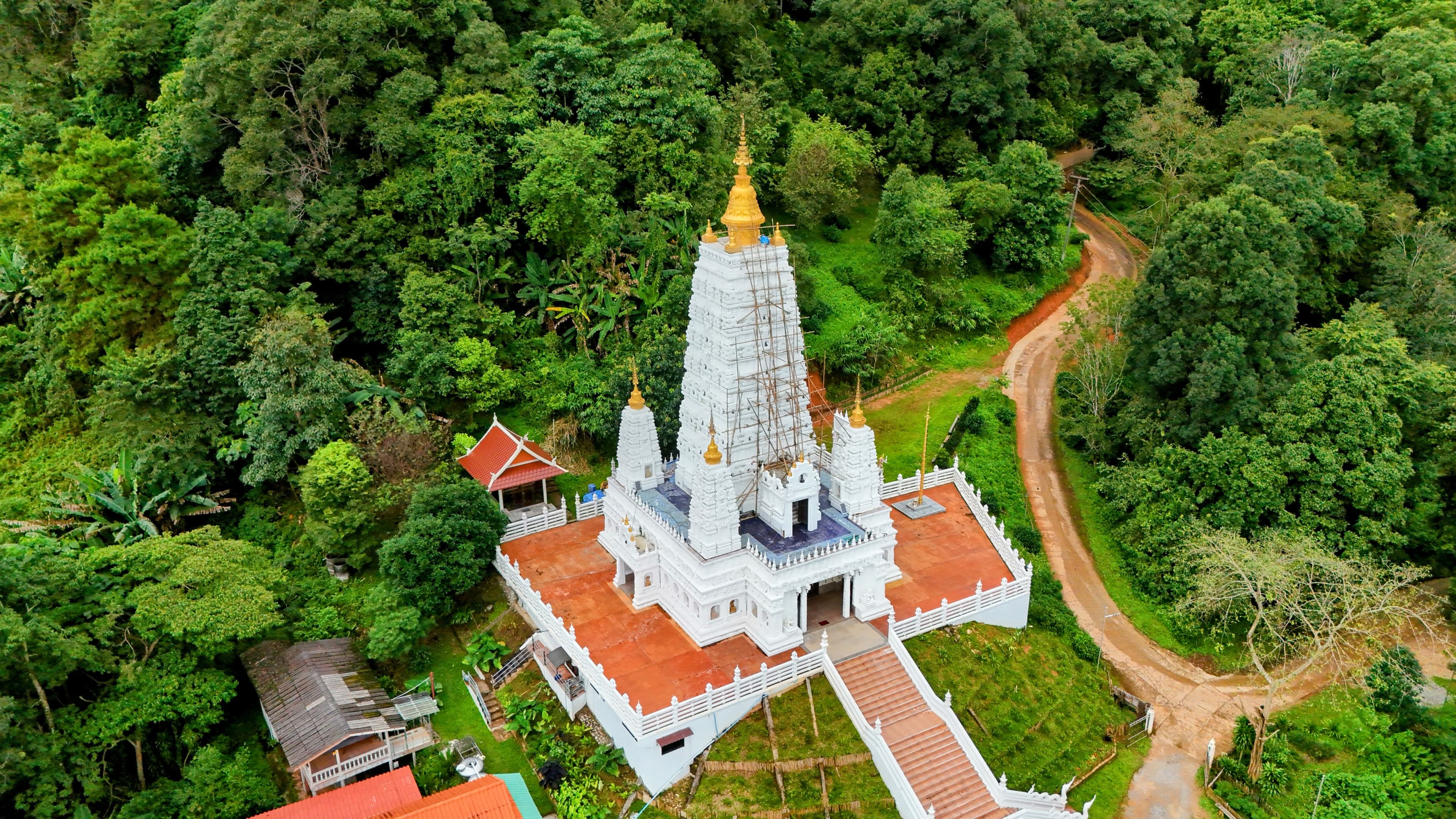 A Mahabodhi-style chedi catching a patch of clearer weather — the visual marker that the dirt is about to start.