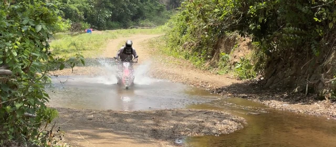A rider crossing a stream on the Mae Hong Son dirt loop