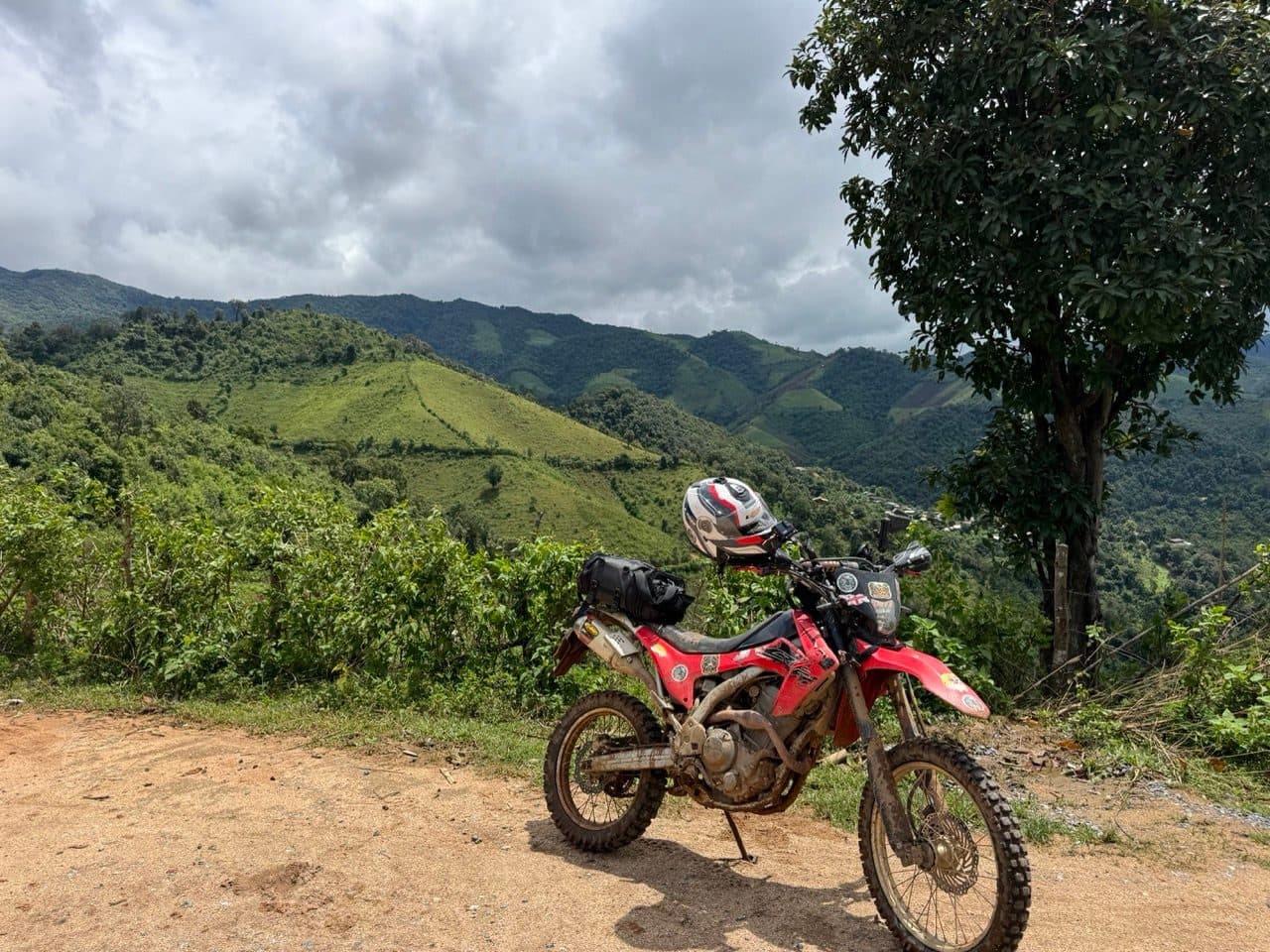 The CRF250L at a viewpoint, hills stacked behind it.