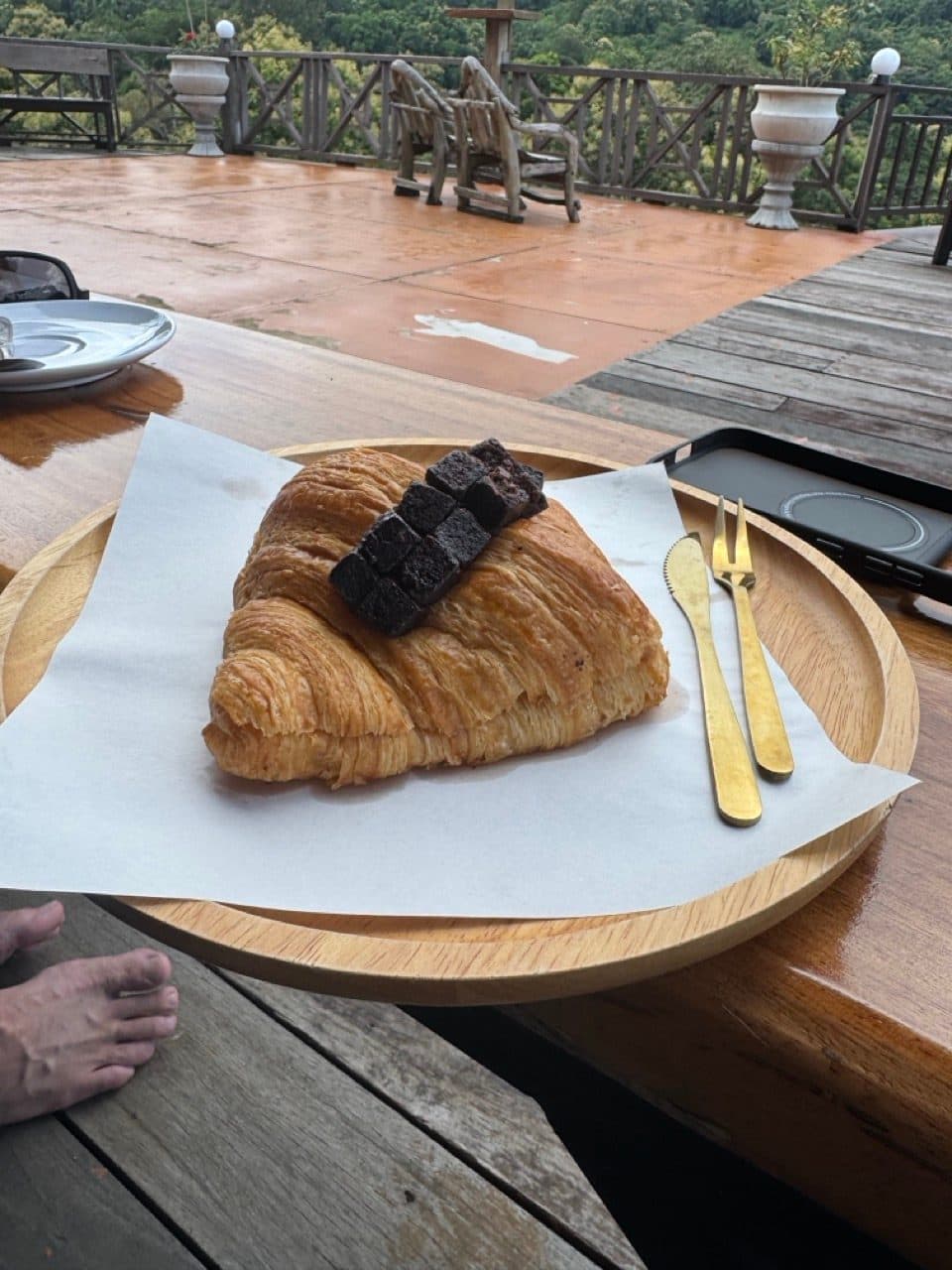 Chocolate croissant on the cafe deck. Boots off.
